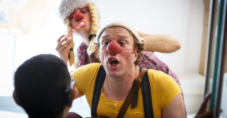 deux clowns : un homme et une femme qui s'amusent avec un enfant en jouant de la musique et en faisant des bulles de savon